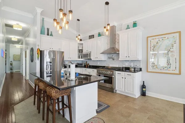 a kitchen with stainless steel appliances kitchen island granite countertop a table chairs and a refrigerator