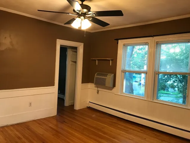 a view of an empty room with a window and wooden floor