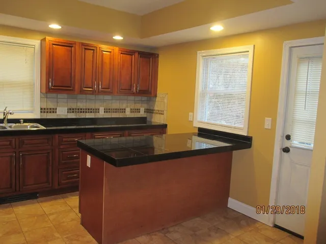 a kitchen with kitchen island granite countertop a sink stainless steel appliances wooden cabinets and a counter top space