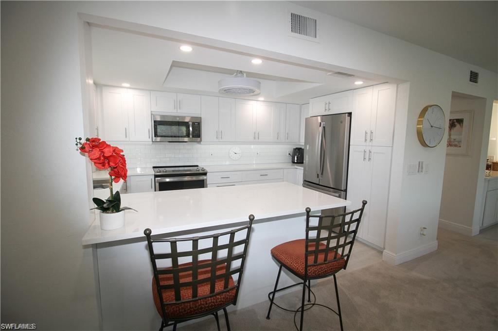 97 Georgetown Boulevard, Unit 97 Naples, FL 34112 - Photo 8 of 25 a kitchen with stainless steel appliances a refrigerator and a dining table