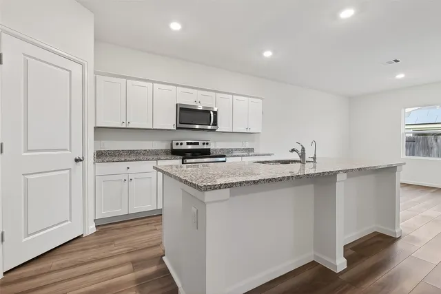 a kitchen with stainless steel appliances granite countertop a stove a sink and a refrigerator