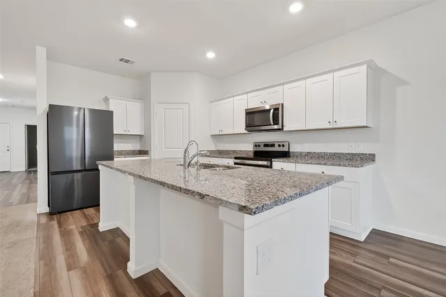 a kitchen with stainless steel appliances granite countertop a kitchen island hardwood floor sink and stove