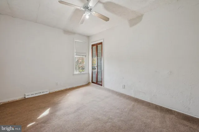 an empty room with a chandelier fan and windows