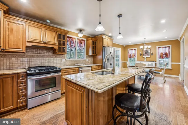 a kitchen with stainless steel appliances granite countertop a stove a sink dishwasher a dining table and chairs with wooden floor