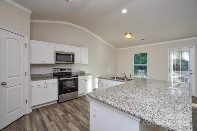 a kitchen with a sink granite counter tops and a window