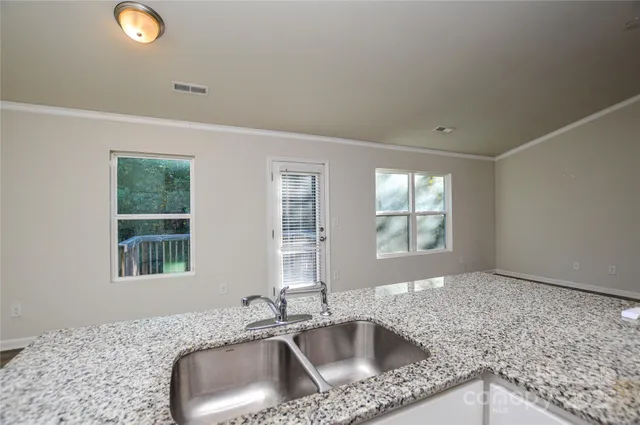 a kitchen with granite countertop white cabinets stainless steel appliances and a counter space