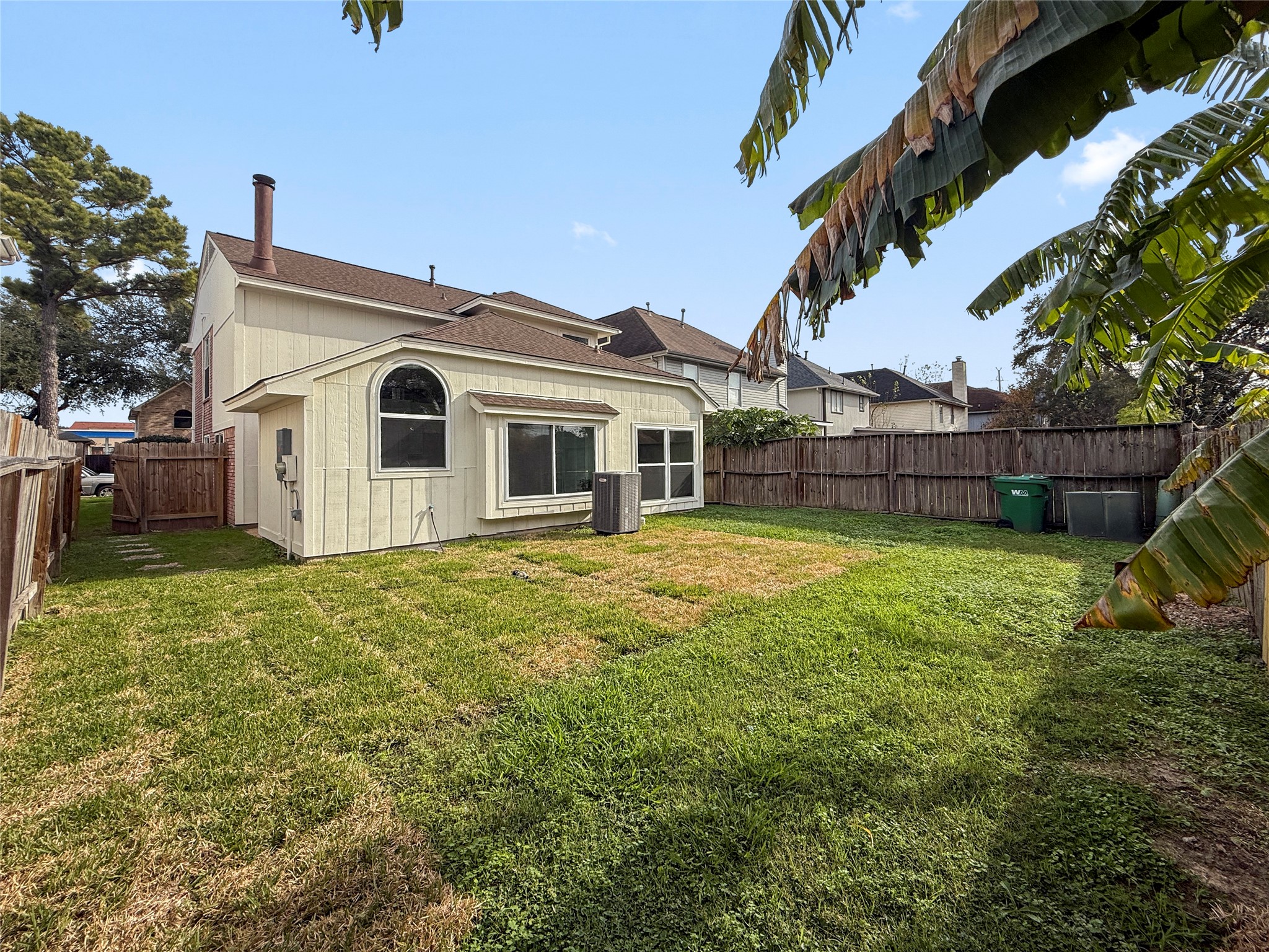 13635 Repa Lane Houston, TX 77014 - Photo 15 of 49 The home has a grassy lawn and a wooden fence. The surrounding trees offer a private and serene outdoor space.