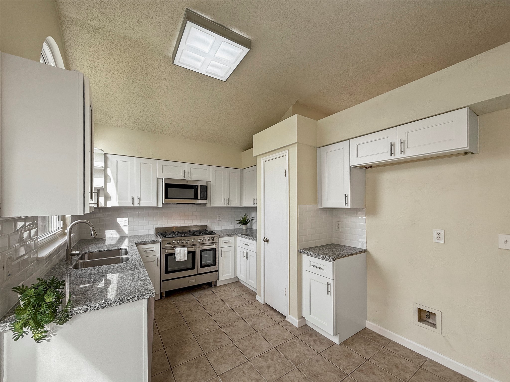 13635 Repa Lane Houston, TX 77014 - Photo 20 of 50 This kitchen features modern white cabinetry, stainless steel appliances, and granite countertops. It has a bright, airy feel with a tile floor and ample storage space.