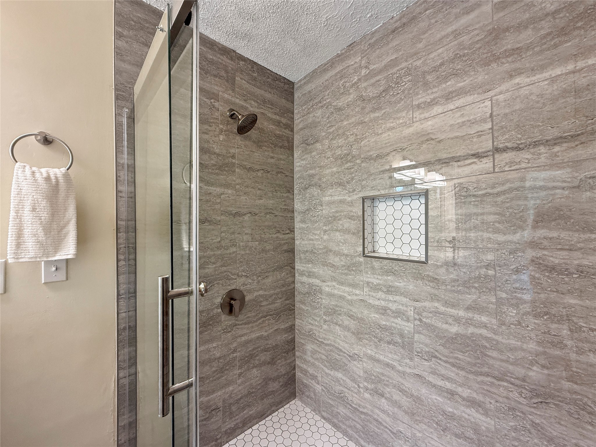 13635 Repa Lane Houston, TX 77014 - Photo 31 of 49 Modern shower with elegant gray tile, glass door, and built-in shelf. Hexagonal tile floor adds a stylish touch.