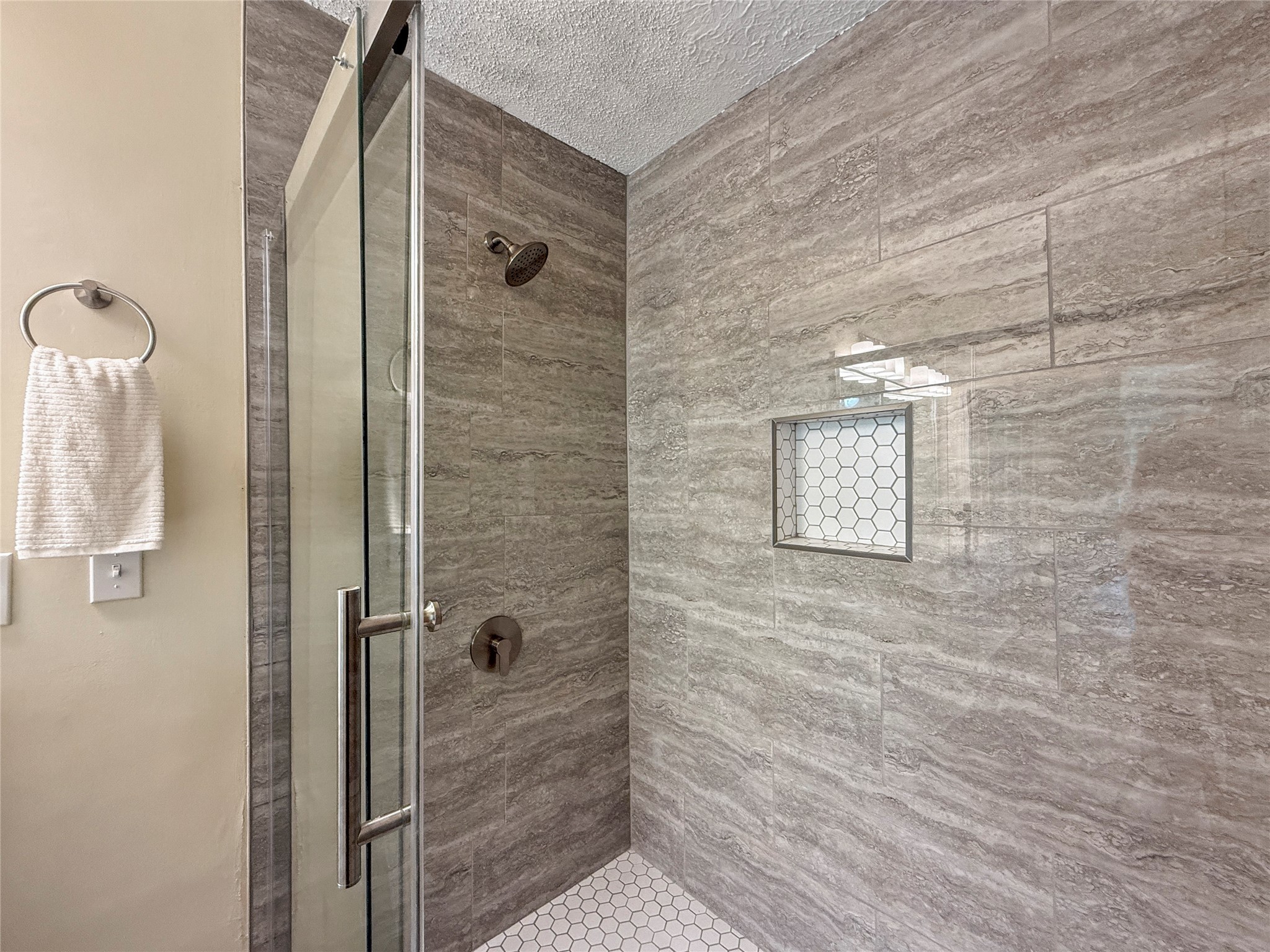 13635 Repa Lane Houston, TX 77014 - Photo 32 of 50 Modern shower with elegant gray tile, glass door, and built-in shelf. Hexagonal tile floor adds a stylish touch.