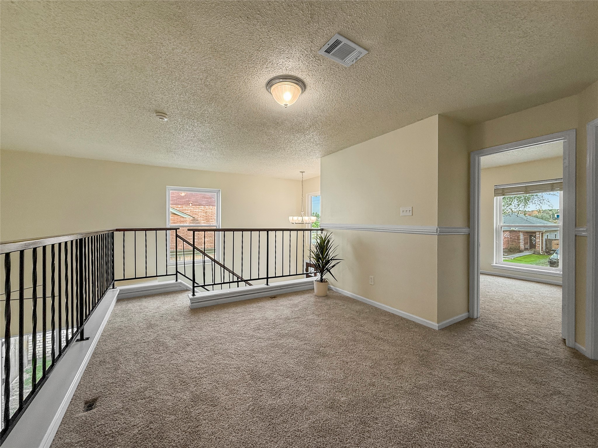 13635 Repa Lane Houston, TX 77014 - Photo 36 of 50 Upstairs, we arrive at this cozy, carpeted loft area with natural light, featuring a railing overlooking the lower level. It leads into three bright rooms with large windows, ideal for extra bedrooms, a home office or reading nook.