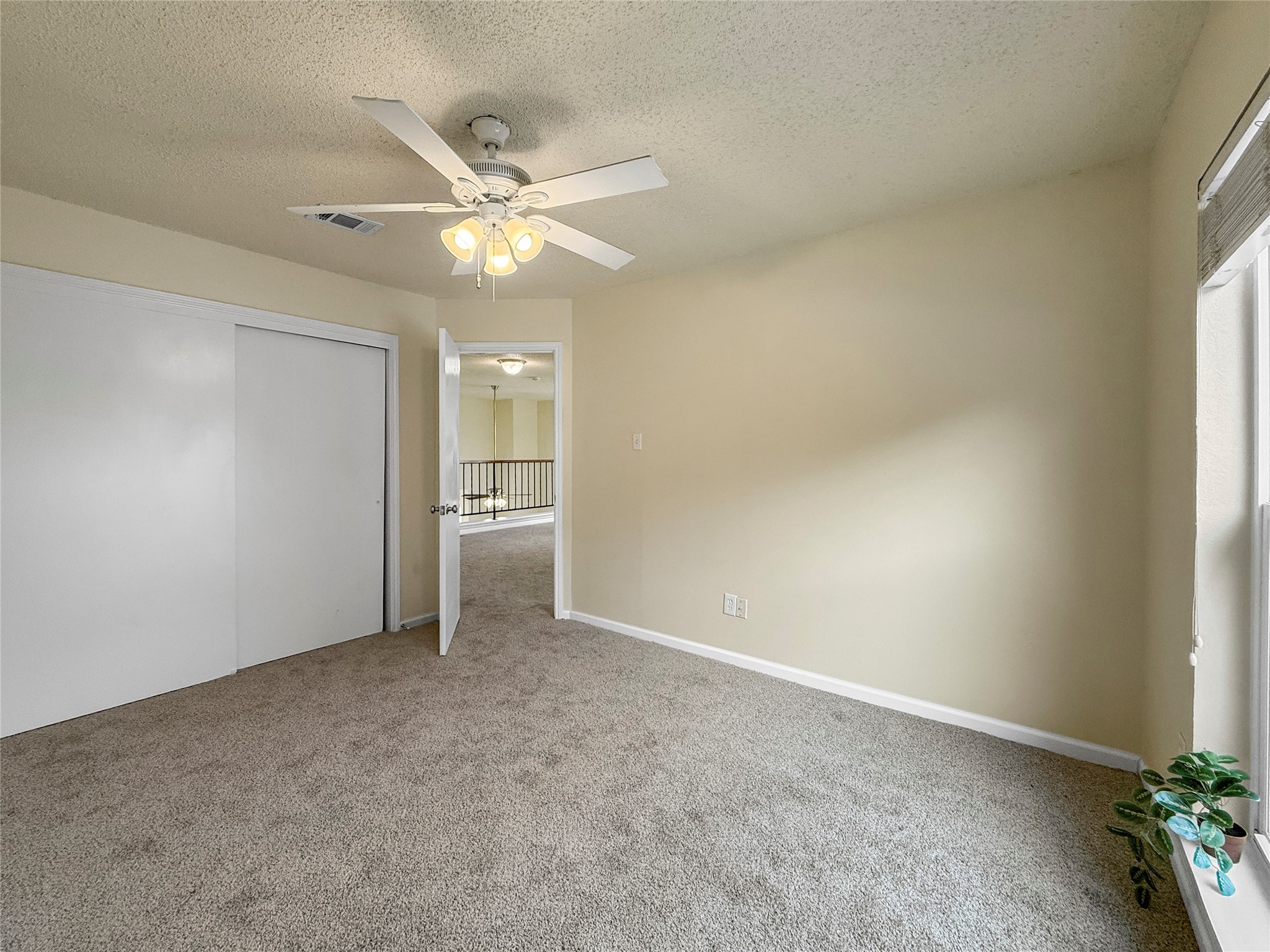 13635 Repa Lane Houston, TX 77014 - Photo 40 of 50 This room features neutral walls and carpet, a ceiling fan with lights, and a large window for natural light, and includes a sliding door closet.