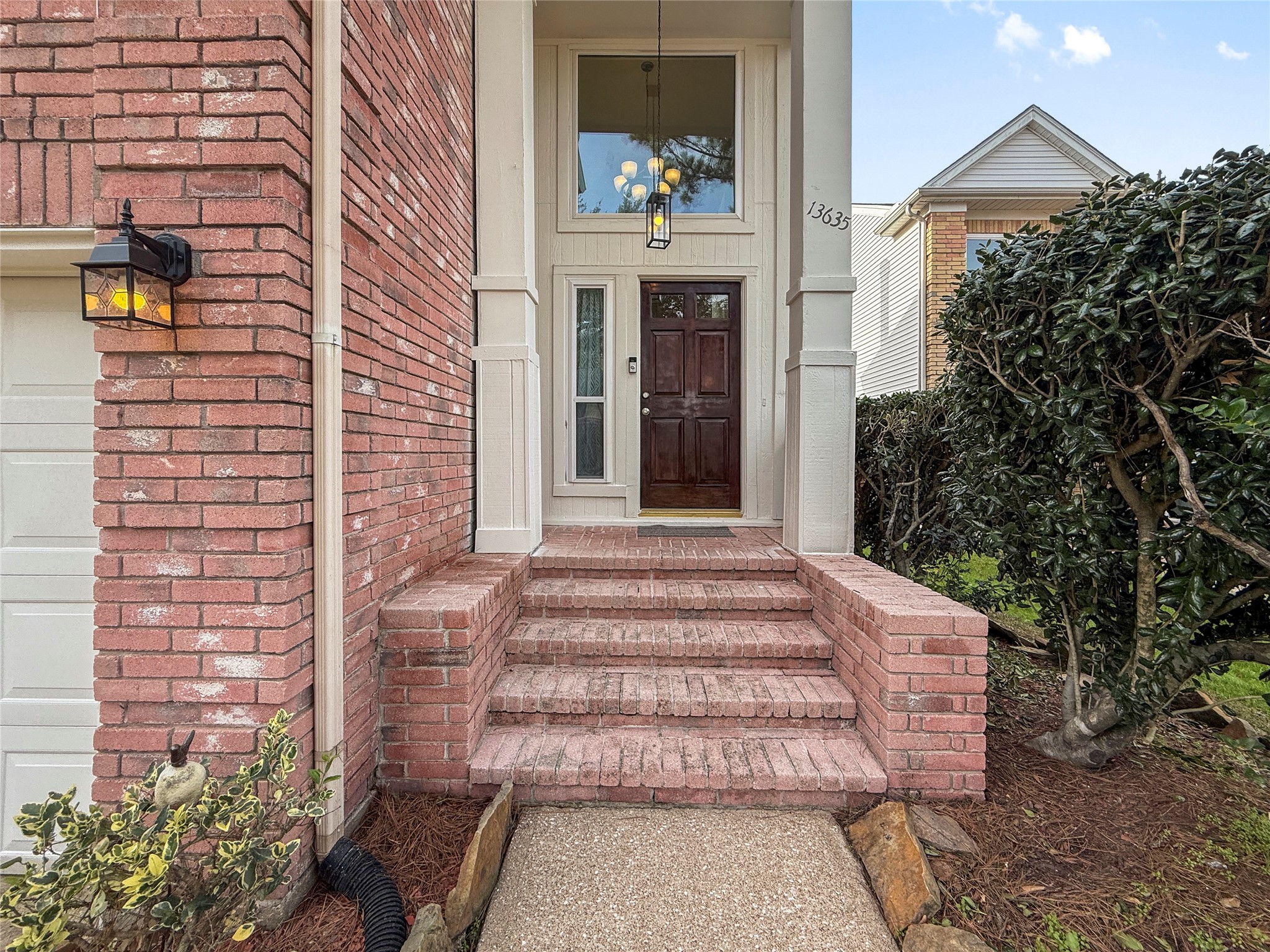 13635 Repa Lane Houston, TX 77014 - Photo 4 of 49 Come on up to this welcoming porch and elegant wooden door, accented by a classic lantern light. The path is bordered by neatly maintained shrubs, providing privacy.
