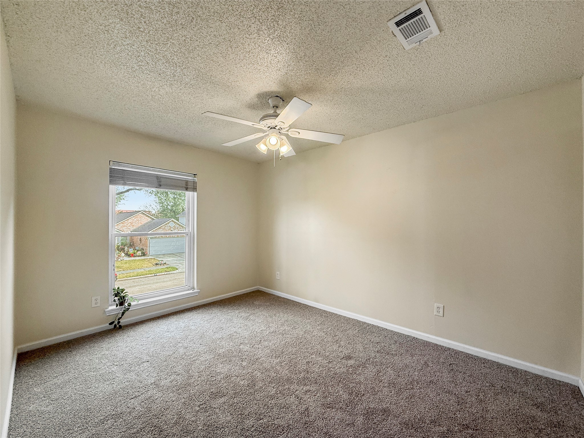 13635 Repa Lane Houston, TX 77014 - Photo 41 of 50 This is a bright, neutral-toned room with fresh carpet and a ceiling fan. The window provides a view of the front yard, driveway and street.