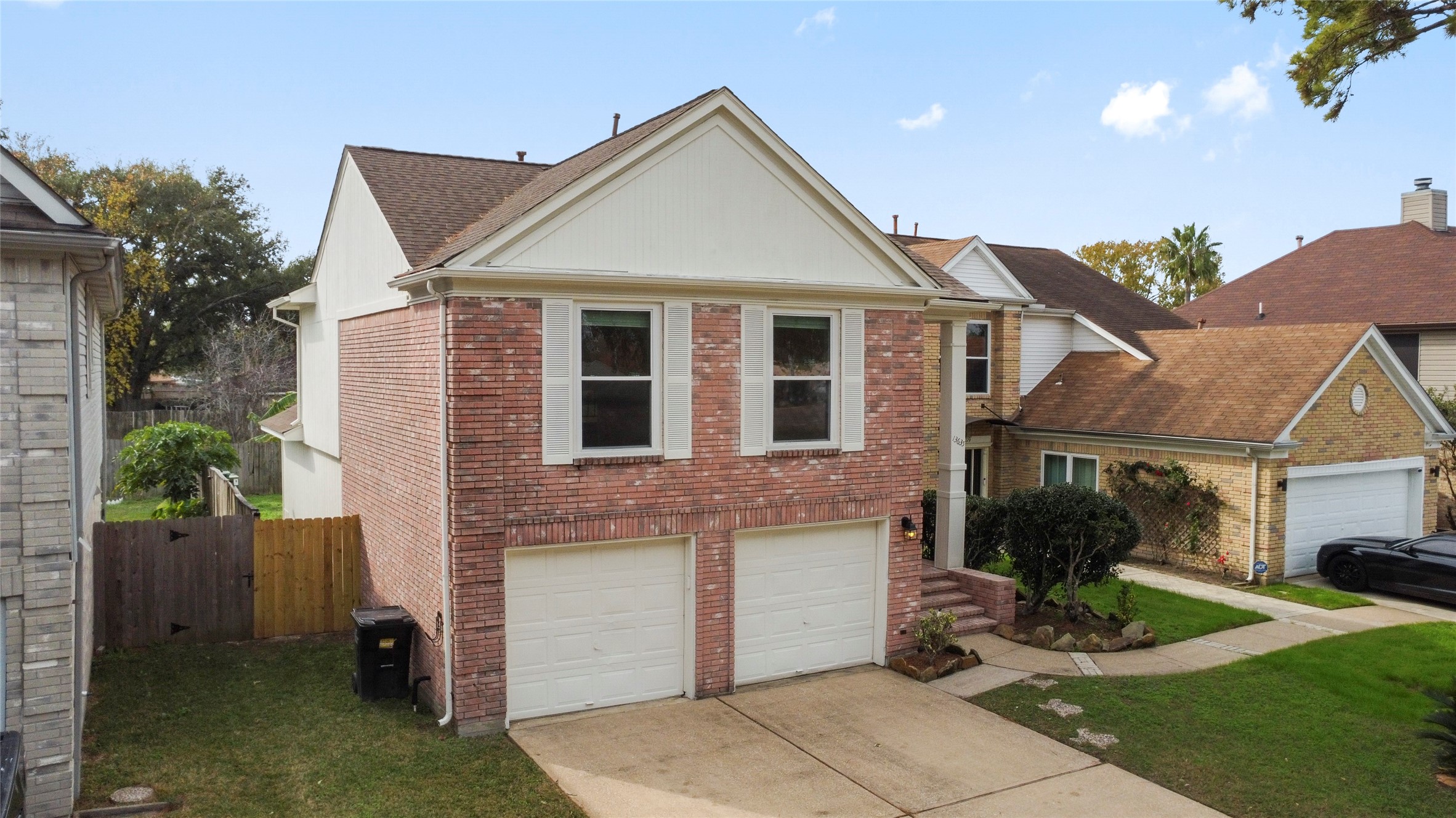 13635 Repa Lane Houston, TX 77014 - Photo 47 of 49 This two-story brick home features a double garage, a small front lawn, and a fenced backyard. It's situated in a suburban neighborhood with neighboring houses closely set. The exterior is well-maintained, offering a welcoming entrance with shrubs and a paved driveway.