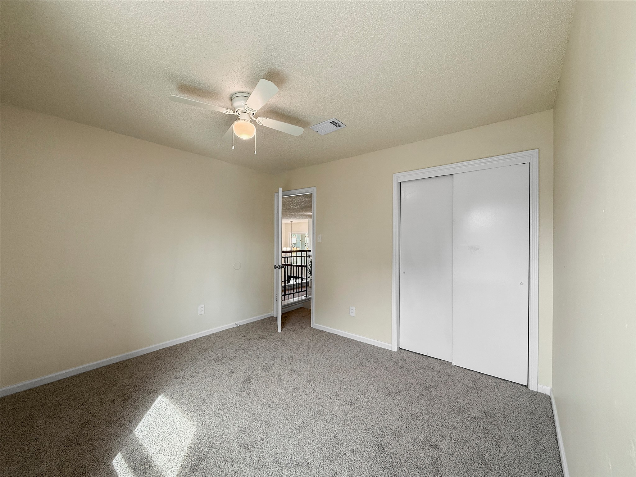 13635 Repa Lane Houston, TX 77014 - Photo 47 of 50 Here's a view of the same bedroom featuring a ceiling fan, a closet with sliding doors, and the doorway leading back to the hallway.