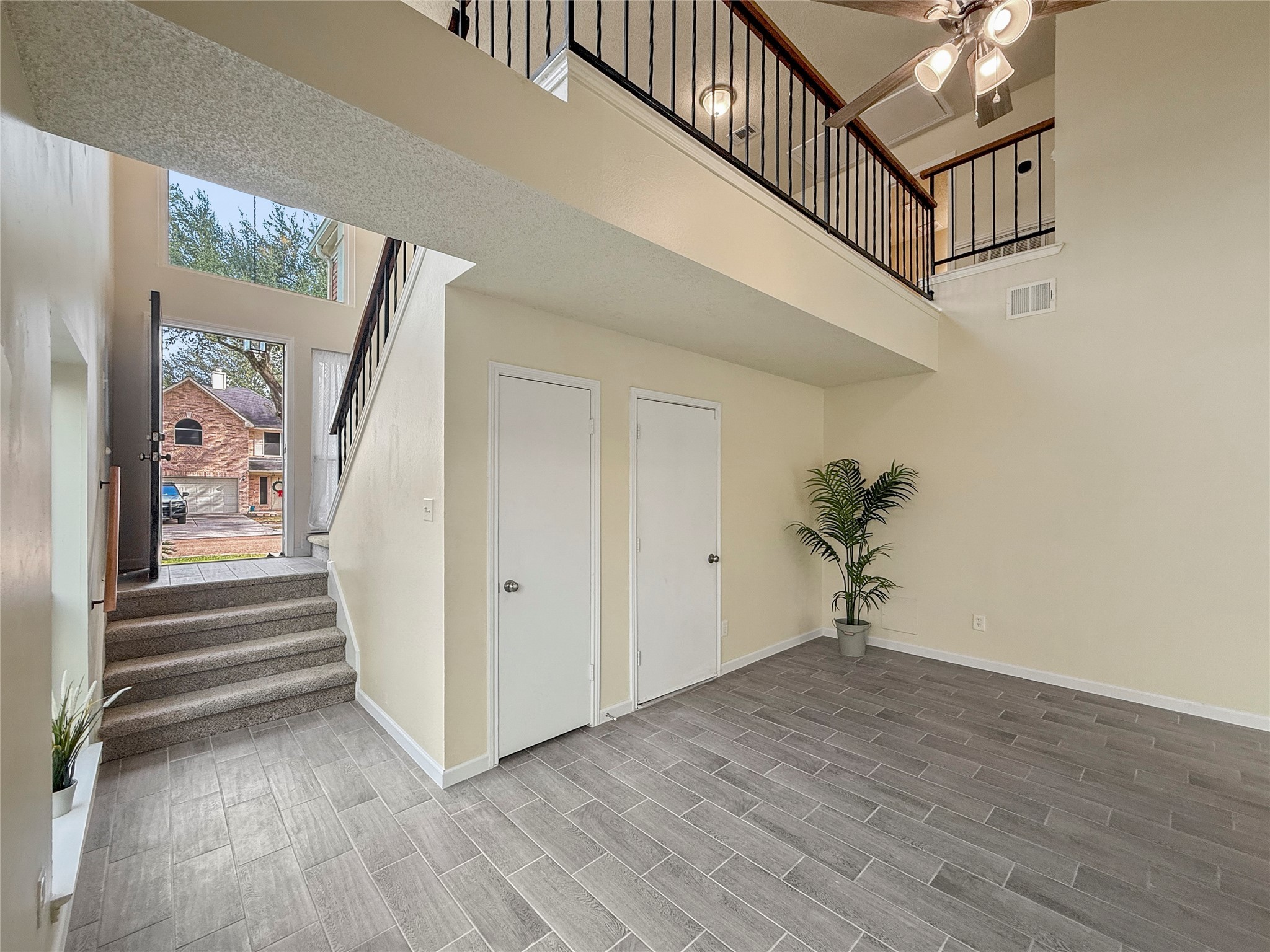 13635 Repa Lane Houston, TX 77014 - Photo 6 of 50 The home has a bright entryway with high ceilings, modern tile flooring, and an open staircase leading to a loft area. Throughout the home you find multiple ceiling fans, neutral walls, and large windows for natural light.