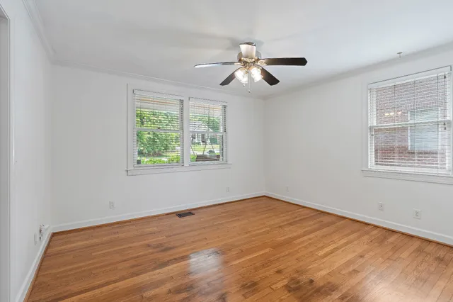 a view of empty room with wooden floor and fan