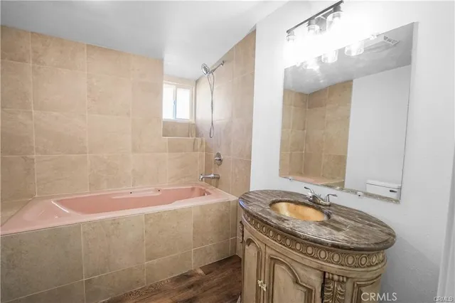 a bathroom with a granite countertop sink a mirror and a bathtub