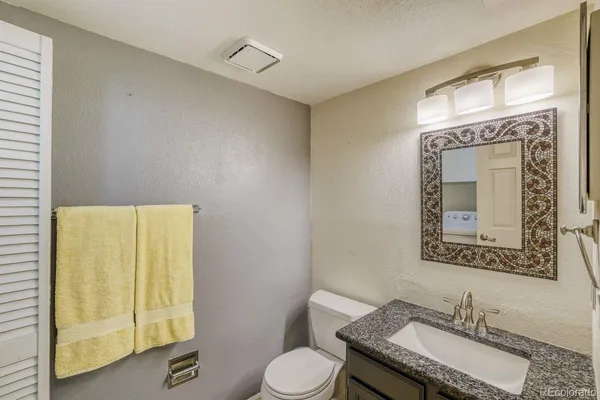 a bathroom with a granite countertop sink mirror vanity and toilet