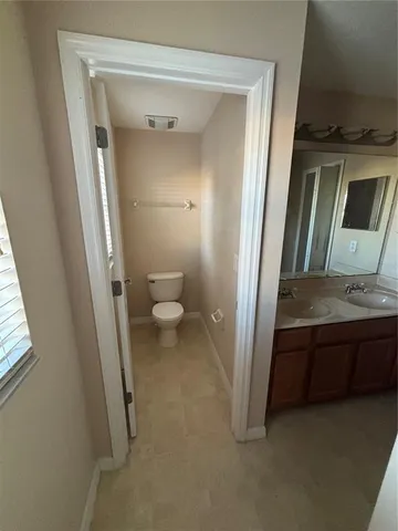 a view of a hallway with wooden floor and a toilet