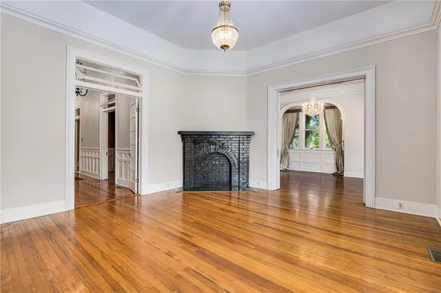 a view of an empty room with wooden floor and a fireplace