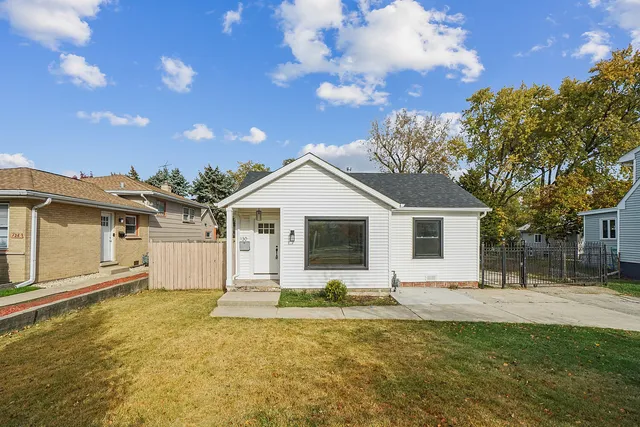 a front view of house with yard and trees in the background