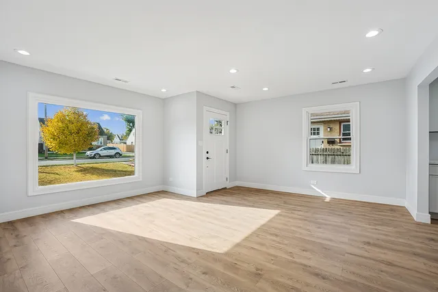 a view of an empty room with window and wooden floor