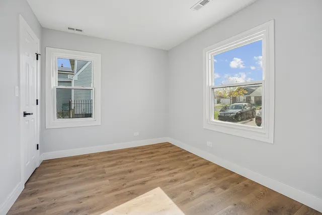 a view of an empty room with a window and wooden floor