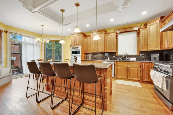 a kitchen with stainless steel appliances granite countertop table chairs and a large window