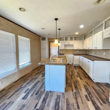 a large kitchen with kitchen island a large window a sink and stainless steel appliances