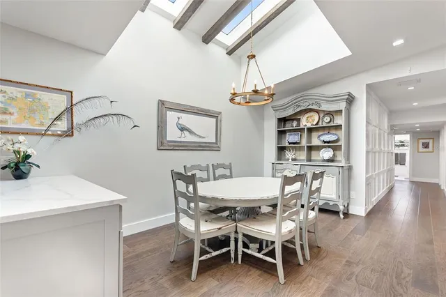 a dining room with wooden floor a chandelier a wooden table and chairs