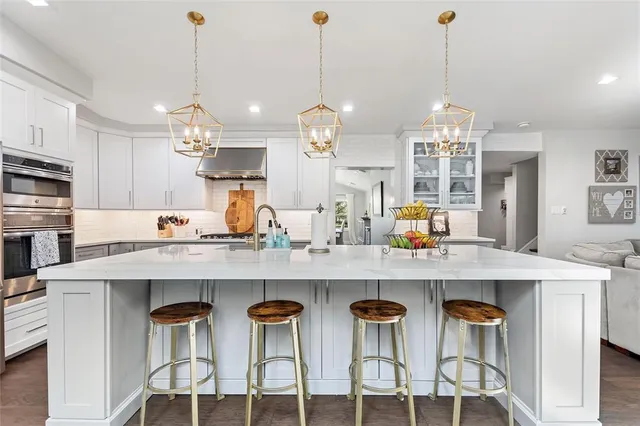 a kitchen with stainless steel appliances kitchen island granite countertop a table chairs in it and wooden floors