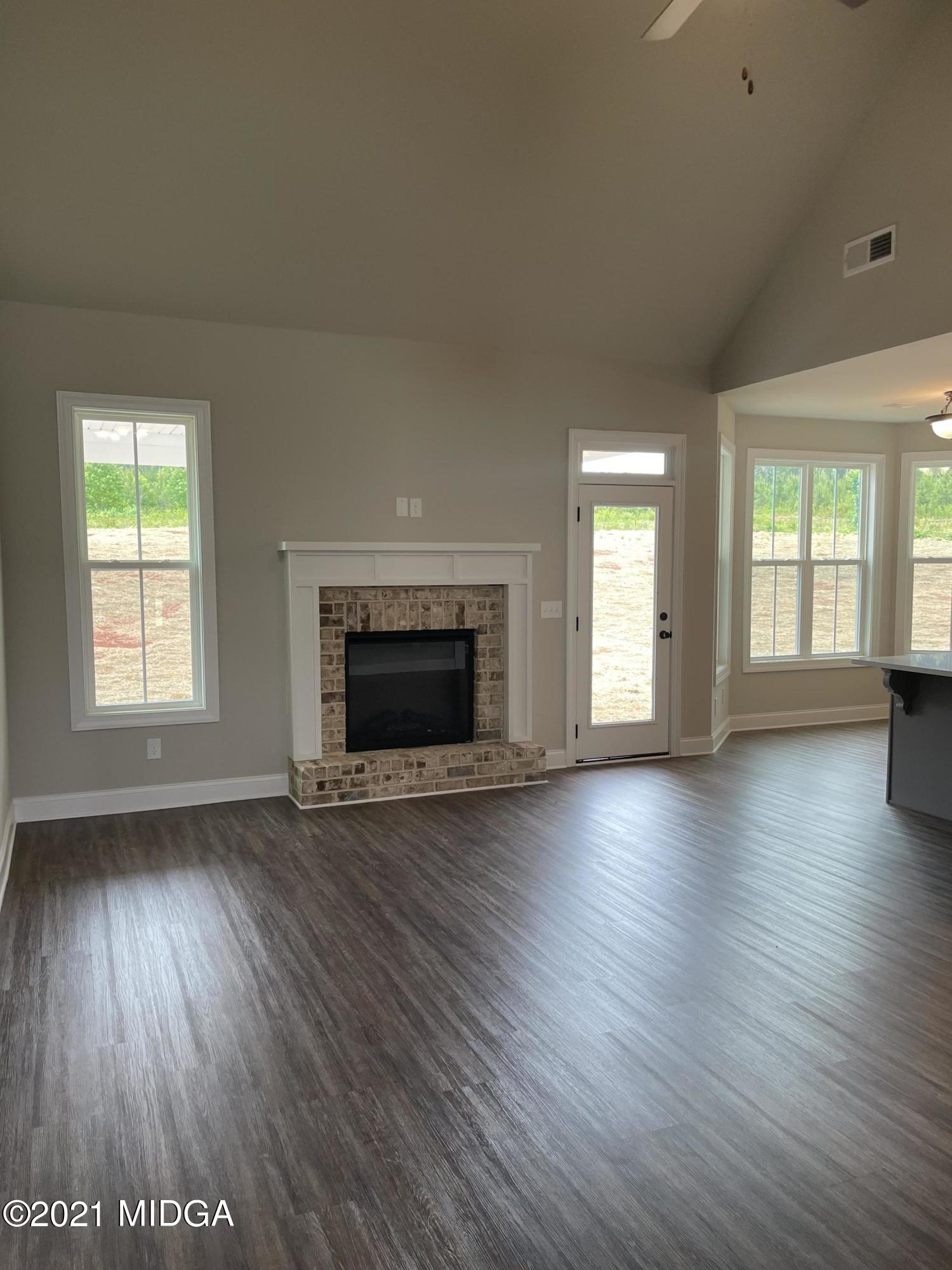 1256 Bunn Road Forsyth, GA 31029 - Photo 5 of 12 an empty room with wooden floor and fireplace