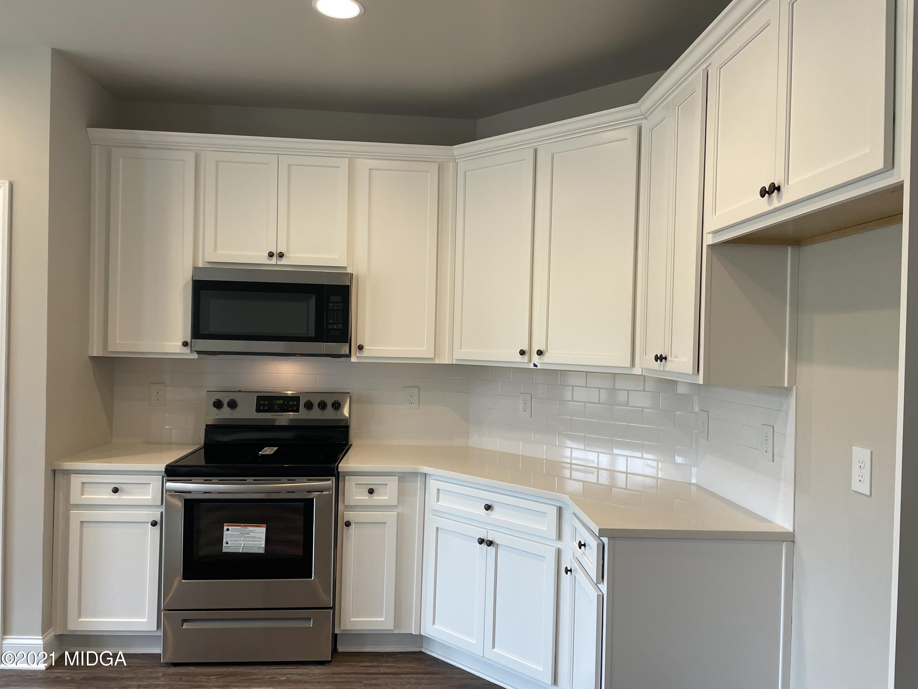 1256 Bunn Road Forsyth, GA 31029 - Photo 8 of 12 a kitchen with white cabinets and black appliances