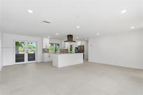 a large white kitchen with a large window and stainless steel appliances