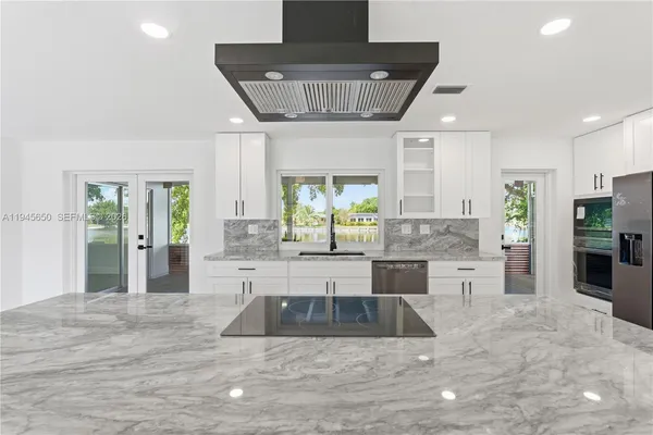 a kitchen with granite countertop a sink and a stove top oven with wooden floor