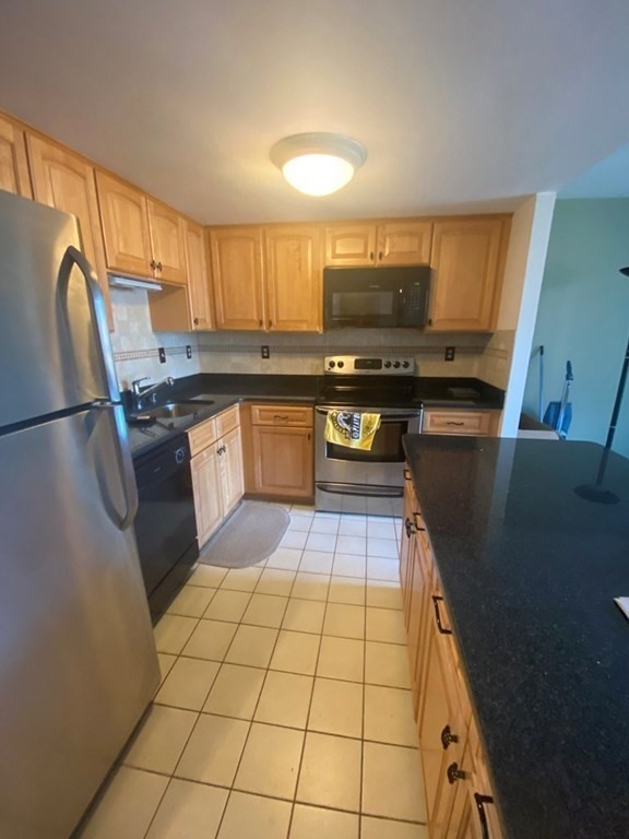 a kitchen with stainless steel appliances granite countertop a sink a stove top oven a counter space and cabinets