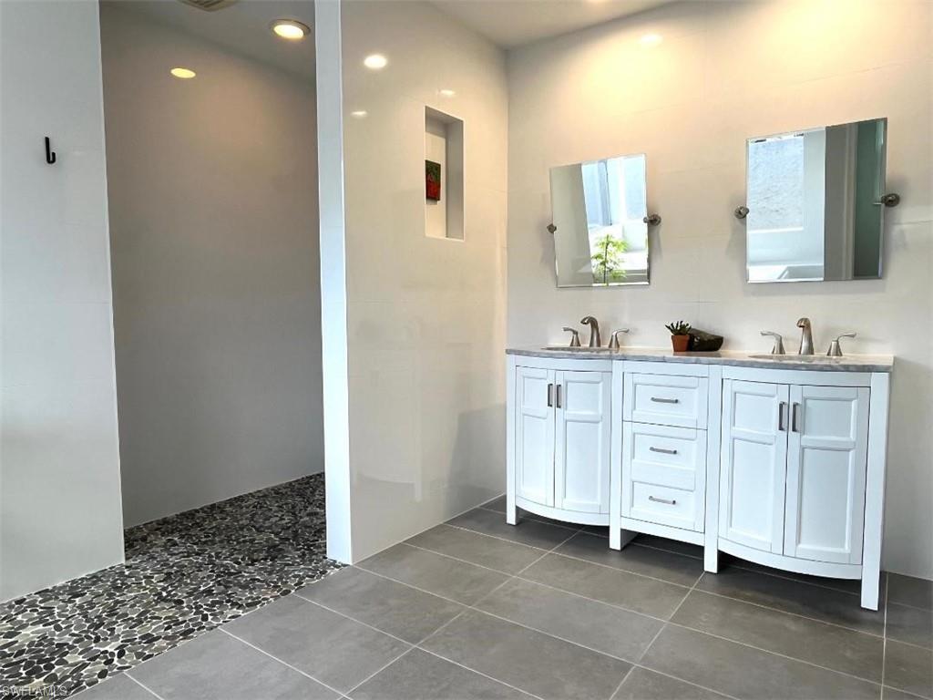 10298 Boca Circle Naples, FL 34109 - Photo 12 of 20 a spacious bathroom with a double vanity sink a mirror and a