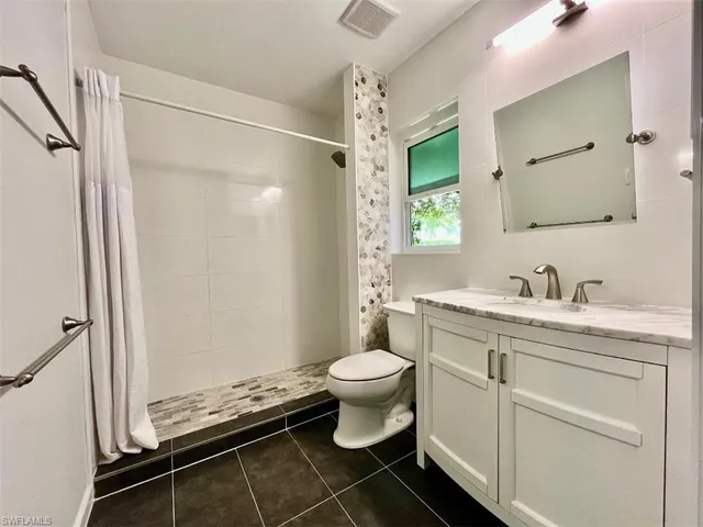a bathroom with a granite countertop sink toilet and shower