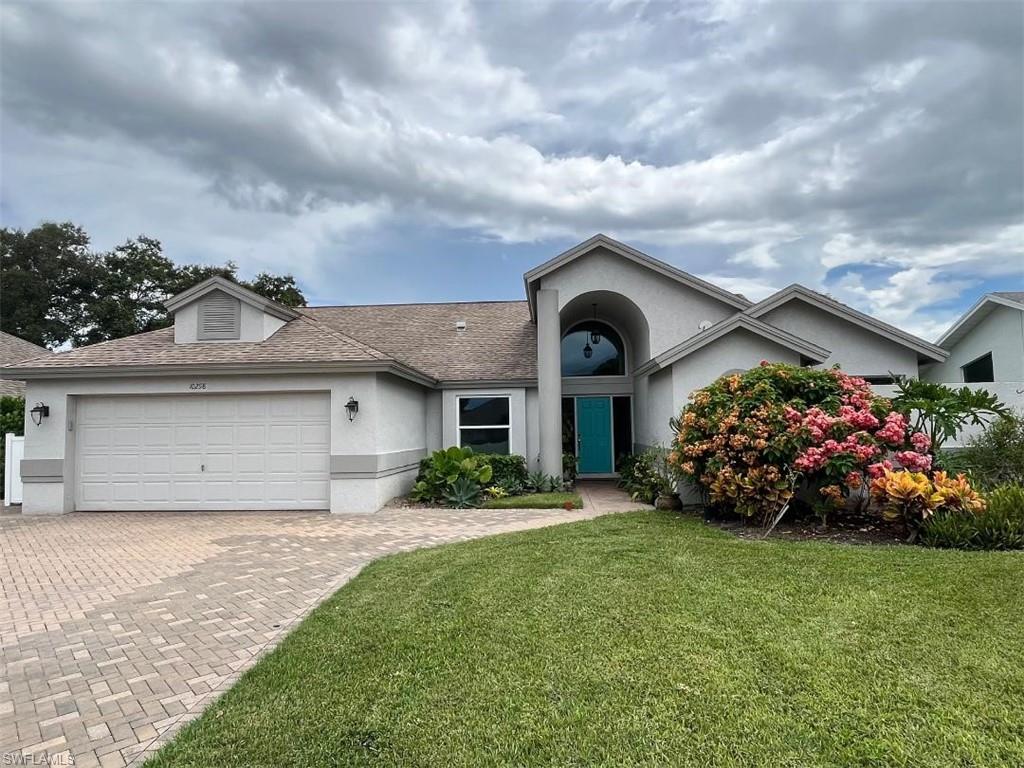 10298 Boca Circle Naples, FL 34109 - Photo 2 of 20 a front view of a house with a garden
