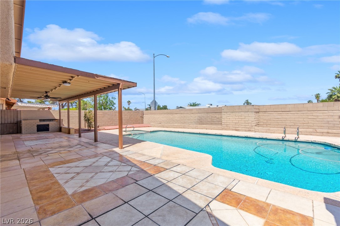 4430 Cranbrook Way Las Vegas, NV 89103 - Photo 23 of 50 An inviting outdoor living space features a covered patio with an outdoor kitchen, complementing the sparkling in-ground pool.