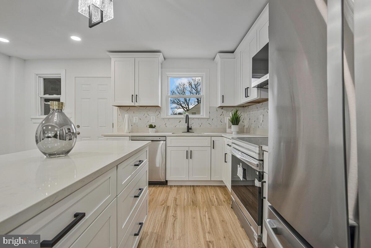 6508 Foster Street District Heights, MD 20747 - Photo 11 of 39 a kitchen with a sink dishwasher stove and white cabinets with wooden floor