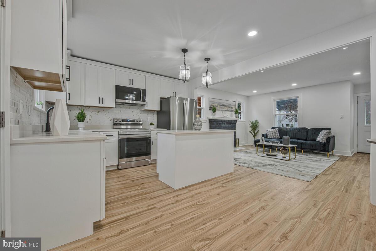 6508 Foster Street District Heights, MD 20747 - Photo 14 of 39 a kitchen with stainless steel appliances kitchen island wooden floors and white cabinets