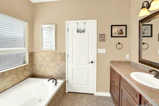 a bathroom with a granite countertop tub sink and mirror