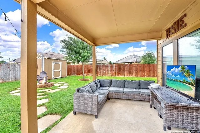 a view of a patio with couches table and chairs with wooden fence and plants