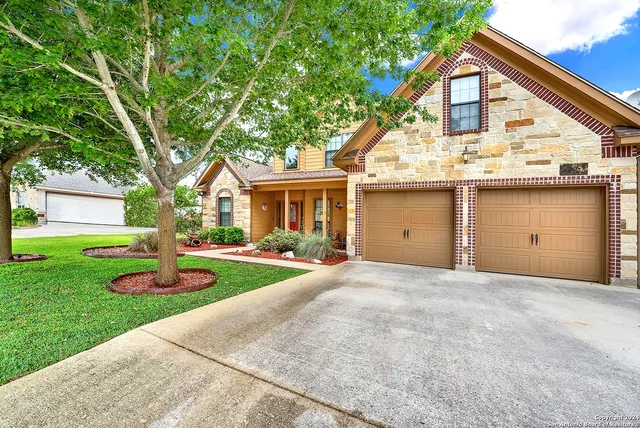a view of a house with a yard and large tree