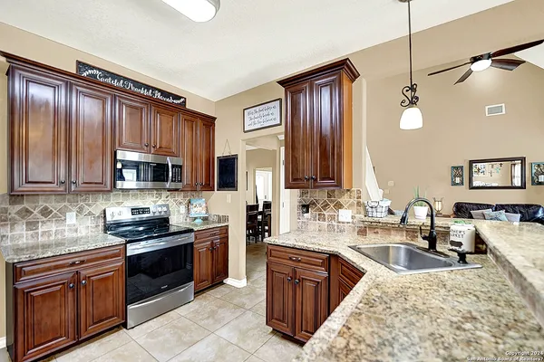 a kitchen with kitchen island granite countertop a sink counter top space appliances and cabinets