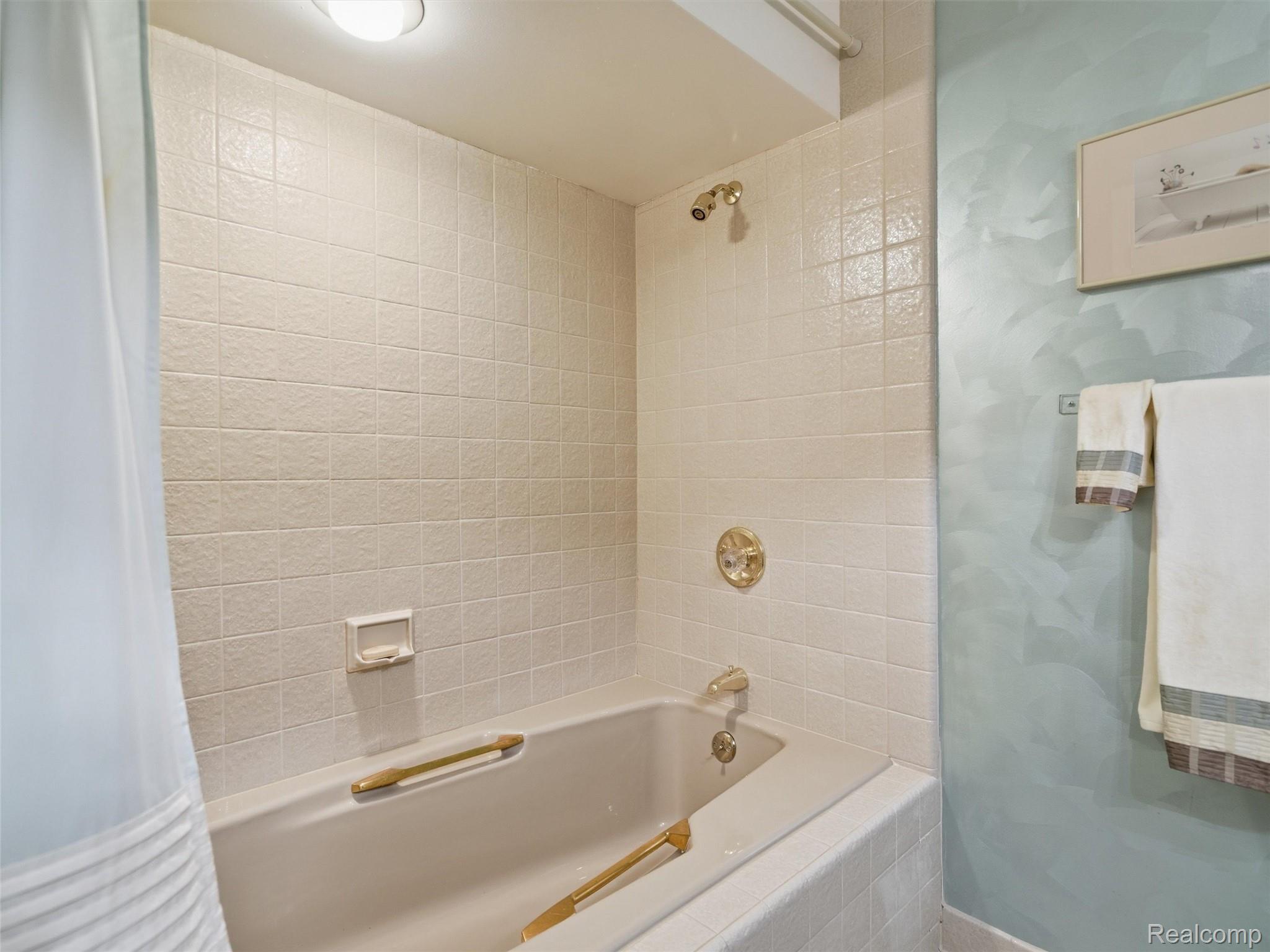 4751 Rolling Ridge Road West Bloomfield, MI 48323 - Photo 40 of 51 LL Bathtub with integrated grab bars, surrounded by light-toned textured tile