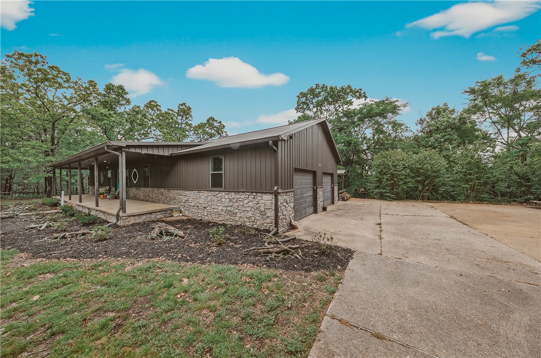 648 Dequeen Lake Road De Queen, AR 71832 - Photo 16 of 46 The property features a covered porch, stone facade, and a two-car garage with a concrete driveway